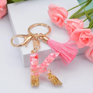 Detail of pink resin letter K keychain with gold foil and matching tassel decoration