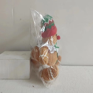 Detailed view of a handmade crochet gingerbread man plush doll with a festive Christmas hat