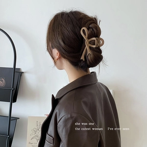 Detail of beige bow-shaped claw clip showing matte finish and secure hair grip on model