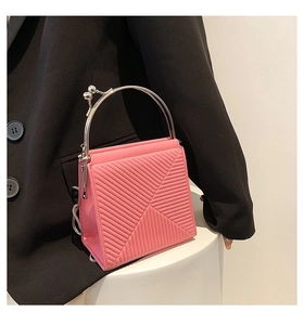 Close-up of pink geometric embossed handbag featuring silver ring handle and vintage clasp