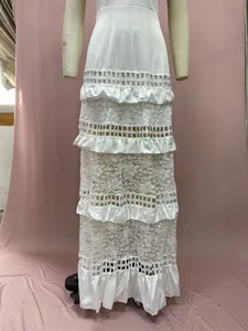 Makro-Detail von weißen gestuften Spitzenvolants und Häkeltexturen an einem Boho-Maxikleid