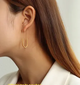Close-up of 18K gold plated safety pin earrings worn by a model in a white suit