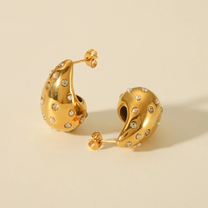 Close-up of teardrop gold earrings featuring white pearls and sparkling crystal stones