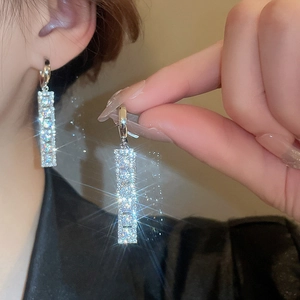 Macro shot of sparkling silver drop earrings with pavé crystals and starburst light effect