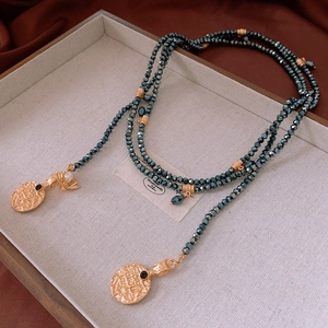 Macro shot of layered vintage beaded necklace with golden medallions and insect charms