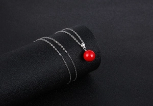 Detailed view of a glossy red bead pendant on a delicate silver necklace chain