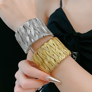 Close-up of vintage braided metal cuff bracelets in gold and silver finish on a wrist