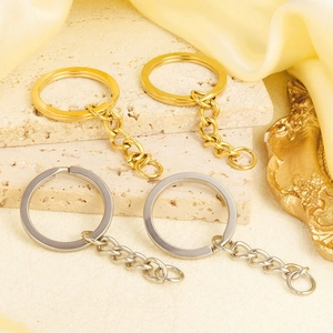 Detail of 18K gold and silver stainless steel keyrings on a textured stone surface