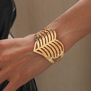 Close-up of golden wide heart cuff bracelet with hammered texture on woman wrist