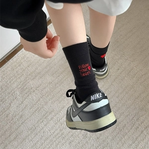 Detailed view of black mid-calf socks featuring red heart embroidery and lettering