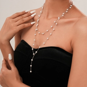 Detail of double-layer silver pearl necklace in Y-shape worn on black clothing
