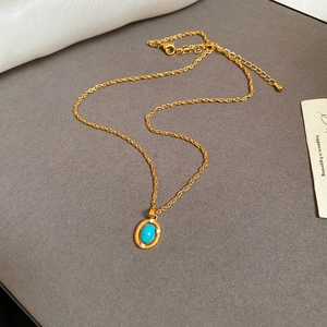 Macro detail of French vintage gold necklace with oval turquoise pendant and small diamonds