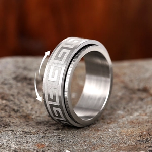 Macro detail of rotating stainless steel ring with Greek fret pattern on stone base