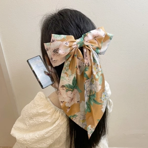 Floral yellow satin bow hair clip worn by a model for a sweet vintage aesthetic look
