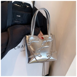 Close-up of silver metallic PU handbag with delicate bow accents and bead chain strap