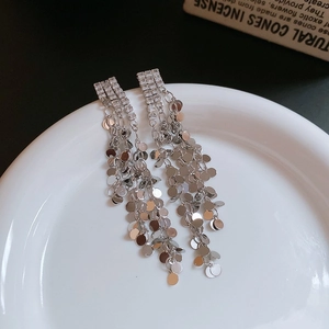 Macro detail of silver long tassel earrings with sparkling rhinestones and metal sequins