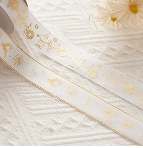 Close-up of white and gold Christmas ribbons with reindeer and snowflake patterns