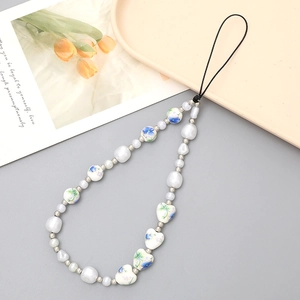 Baroque pearl phone strap with heart-shaped floral ceramic beads on a neutral background
