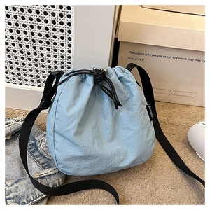 Detailed view of light blue nylon bucket bag with adjustable black strap and drawstring