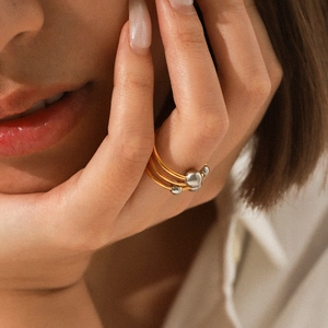 Detail view of a triple-layered gold ring featuring three silver spherical bead accents