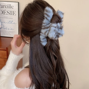 Detail of blue and gray striped plush hair claw clip worn on a model's head
