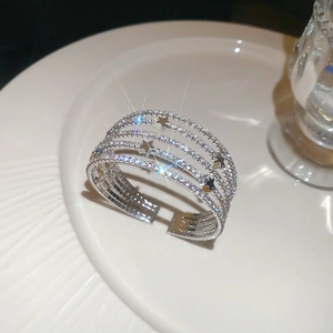 Macro d'un bracelet multicouche argenté avec strass et détail d'étoile sur plateau blanc