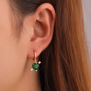 Cupid's heart arrow earrings with green gemstone and gold finish on model