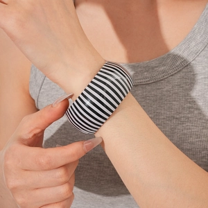 Detailed view of a wide black and white striped cuff bracelet on a model wrist