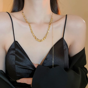 Dettaglio collana dorata con nappe e motivo a spiga di grano su collo modella