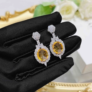 Macro detail of silver drop earrings with large oval yellow gemstone and marquise diamonds