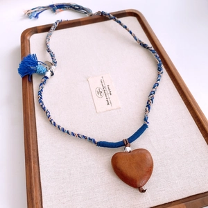 Detailed shot of a handcrafted heart-shaped wooden pendant with colorful woven cotton rope