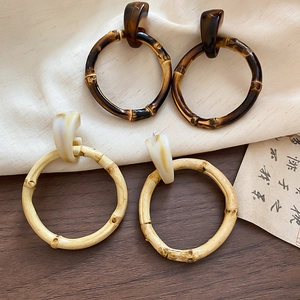 Detail of round resin earrings with bamboo texture in brown and light wood finishes