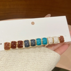 Detail of vintage multicolor long hair clip with marbled resin blocks in gold setting