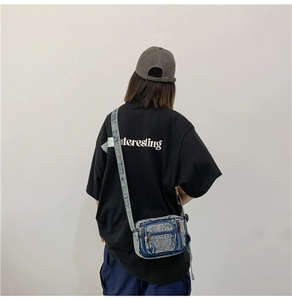 Rear view of a vintage washed denim crossbody bag worn with a casual black t-shirt