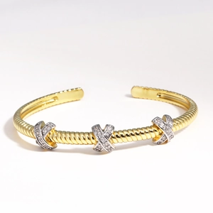 Détail d'un bracelet jonc torsadé doré orné de motifs X en argent sertis de diamants