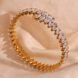 Dettaglio macro del bracciale dorato con zirconi marquise su elegante raso champagne