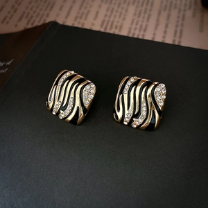 Detailed view of vintage gold rhombus earrings with tiger pattern and sparkling crystals