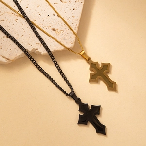 Detalle de los collares de cruz de acero inoxidable en oro y negro sobre piedra