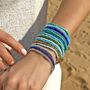 Detailopname van kleurrijke boho kralenarmbanden op een zonnige strandachtergrond