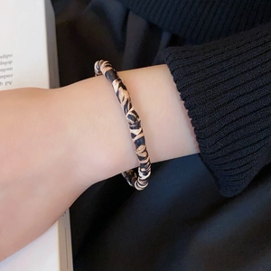 Close-up of leopard print twist bracelet worn on wrist with elegant fabric texture