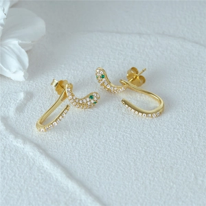 Detailed macro view of S925 sterling silver stamp on golden snake earrings with green gems