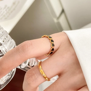Detail of stacked gold rings with black heart enamel and sparkling cubic zirconia stones