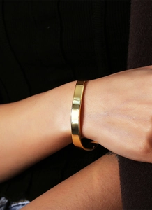 Detail of minimalist gold plated brass cuff on wrist with smooth polished finish