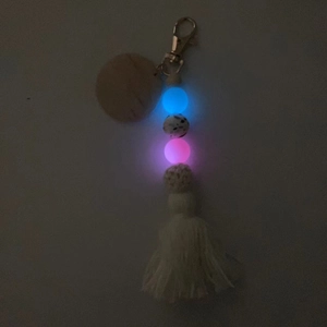 Porte-clés en perles lumineuses avec disque en bois et pompon brillant dans le noir
