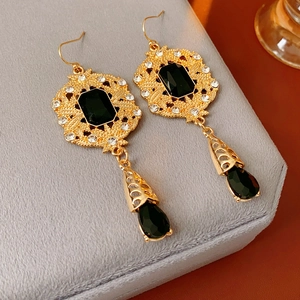 Close-up of vintage royal style gold-plated earrings with black teardrop gemstones