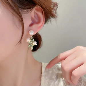 Élégantes boucles d'oreilles muguet avec perles et feuilles vertes sur un mannequin