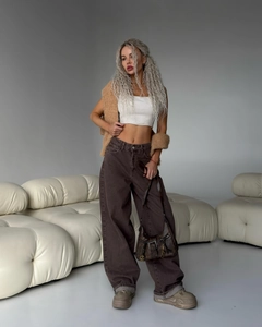 Dettaglio di jeans a zampa a vita bassa marrone caffè con crop top e gilet in maglia