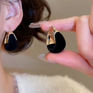 Close-up of vintage black velvet U-shaped hoop earrings with gold-toned metal accents