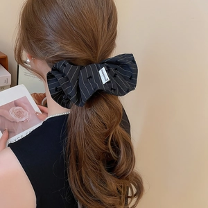Vue arrière d'un modèle portant un chouchou à nœud rayé noir avec étiquette en tissu