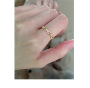 Detailed close-up of golden chain link ring with sparkling crystals on model hand